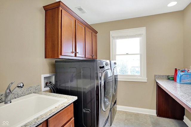 clothes washing area featuring washing machine and clothes dryer, visible vents, baseboards, cabinet space, and a sink