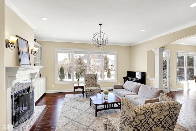 living area with dark wood-type flooring, ornamental molding, arched walkways, decorative columns, and baseboards