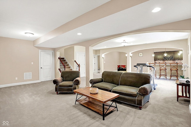 living room featuring visible vents, light carpet, recessed lighting, stairway, and arched walkways