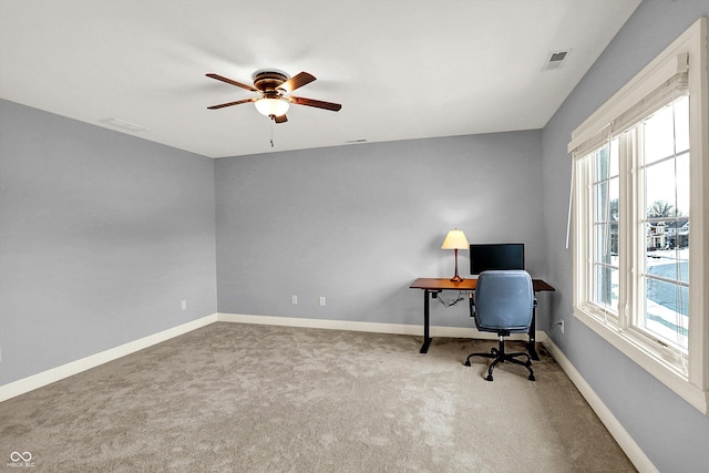 carpeted home office with a ceiling fan, baseboards, and visible vents