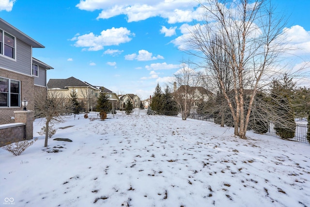 yard covered in snow featuring a residential view and fence