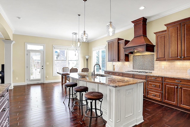 kitchen featuring backsplash, dark wood-style floors, stainless steel gas stovetop, custom exhaust hood, and a sink