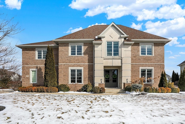 traditional-style house featuring french doors, brick siding, and a shingled roof