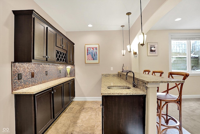 kitchen featuring dark brown cabinets, a peninsula, a breakfast bar area, and a sink