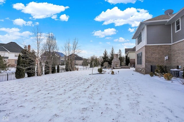 snowy yard with a garage, central AC, and fence