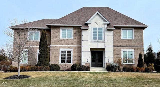 traditional home featuring brick siding, french doors, a front lawn, and roof with shingles