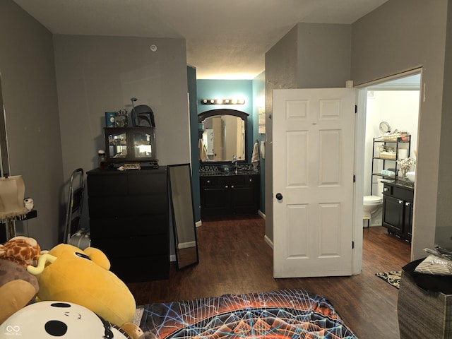 bedroom with dark wood-type flooring, connected bathroom, and a sink