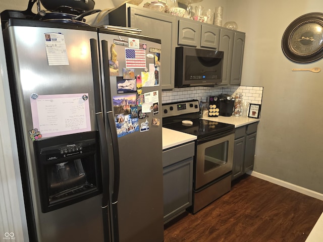 kitchen featuring light countertops, appliances with stainless steel finishes, gray cabinets, decorative backsplash, and dark wood-style floors