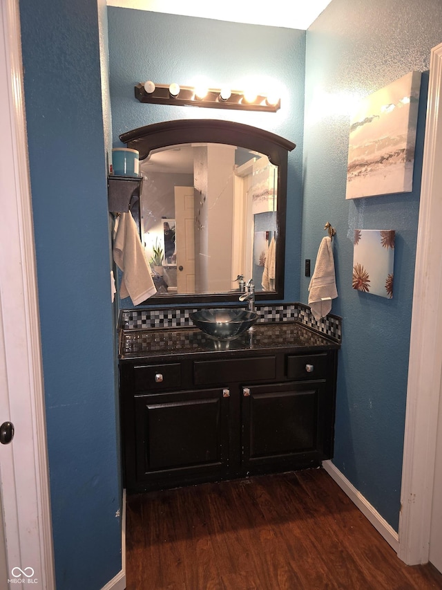 bathroom featuring a textured wall, vanity, baseboards, and wood finished floors