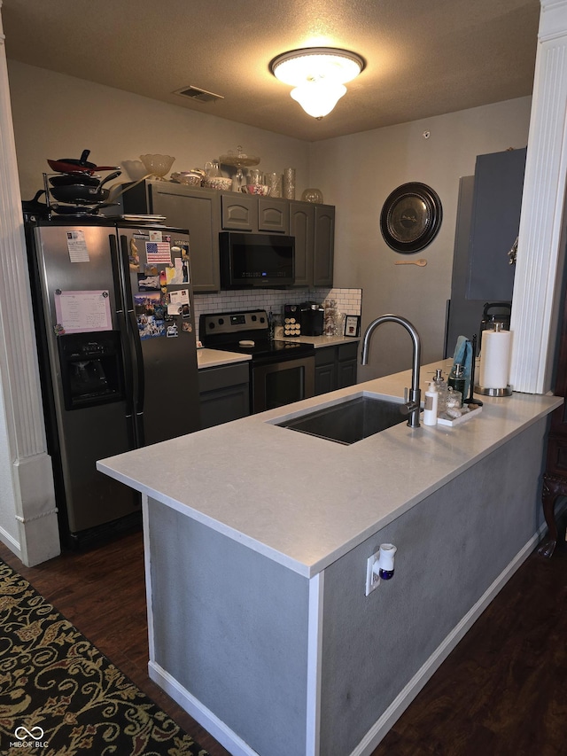 kitchen with dark wood-style flooring, stainless steel appliances, gray cabinets, visible vents, and a sink