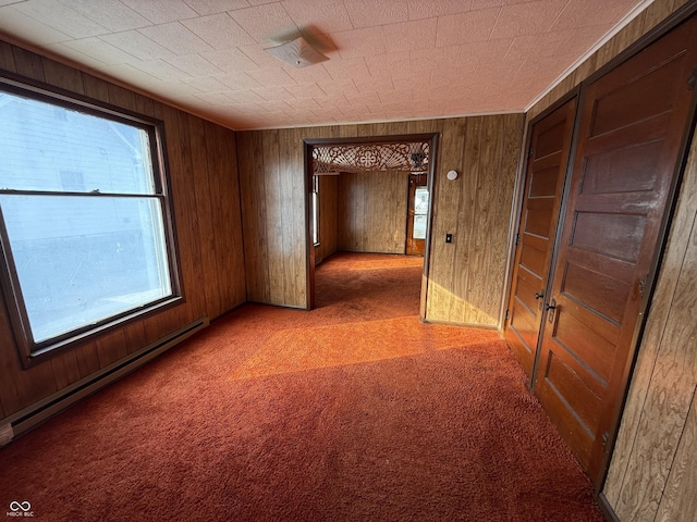 empty room with a baseboard heating unit, light carpet, and wood walls