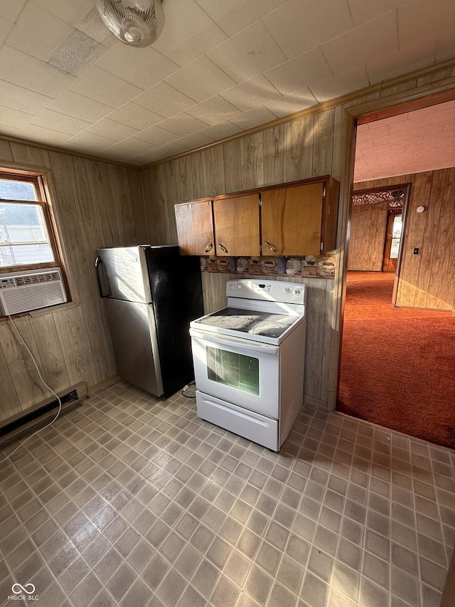 kitchen with cooling unit, white electric stove, freestanding refrigerator, wood walls, and brown cabinets