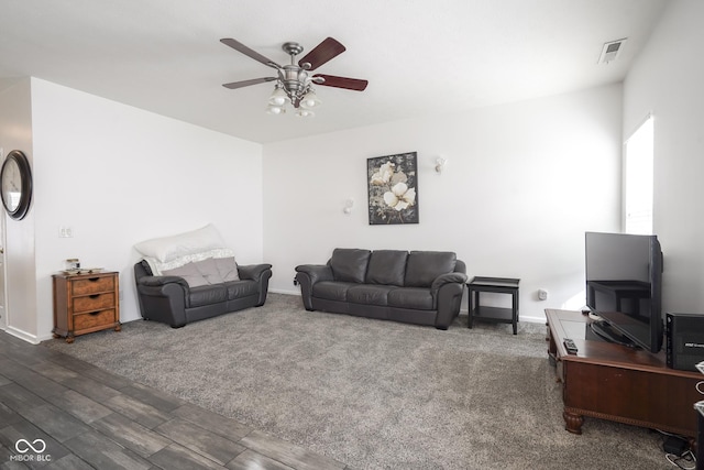 carpeted living room with baseboards, visible vents, a ceiling fan, and wood finished floors