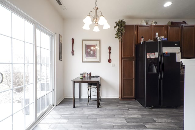 kitchen featuring visible vents, light wood-type flooring, black fridge with ice dispenser, and a wealth of natural light