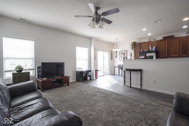 living room with baseboards, wood finished floors, ceiling fan with notable chandelier, a textured ceiling, and recessed lighting