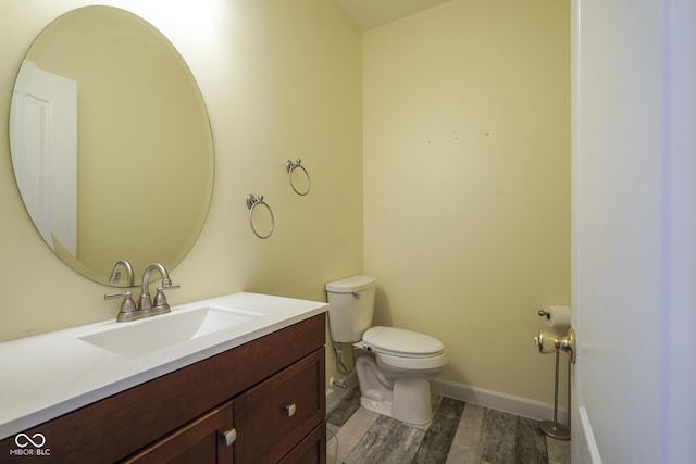 bathroom with vanity, wood finished floors, toilet, and baseboards