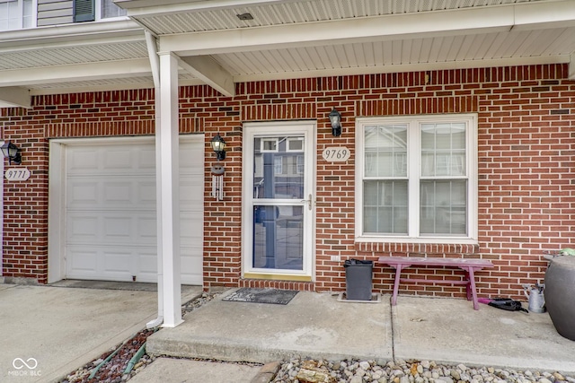 property entrance with a garage and brick siding