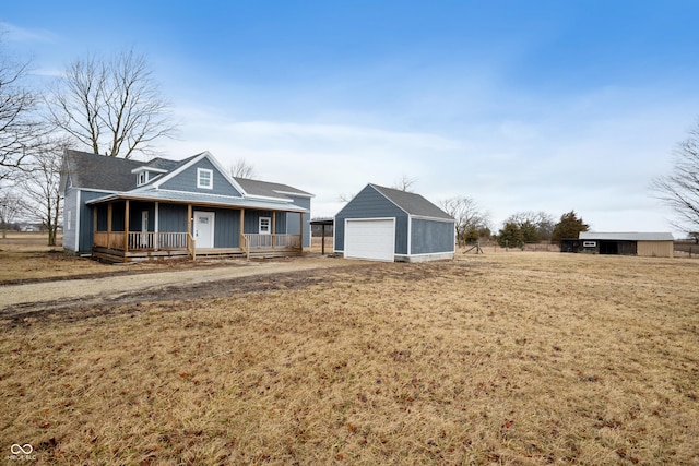 view of front of house with an outbuilding, a porch, a detached garage, and a front yard