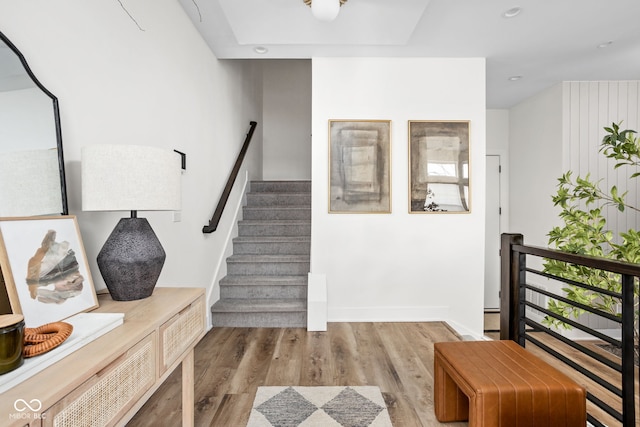 stairway featuring baseboards, wood finished floors, and recessed lighting