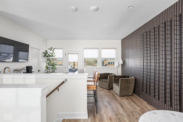 kitchen with light wood-type flooring, wood walls, a sink, and recessed lighting