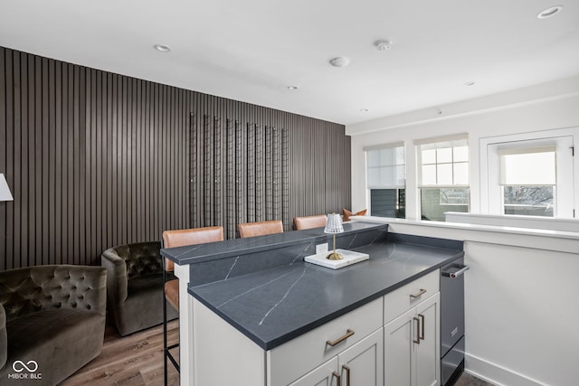 kitchen featuring a breakfast bar, dark countertops, recessed lighting, dark wood-type flooring, and white cabinets