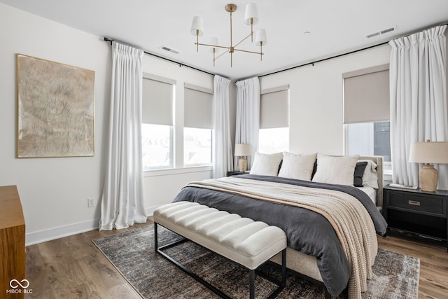 bedroom with an inviting chandelier, baseboards, visible vents, and wood finished floors