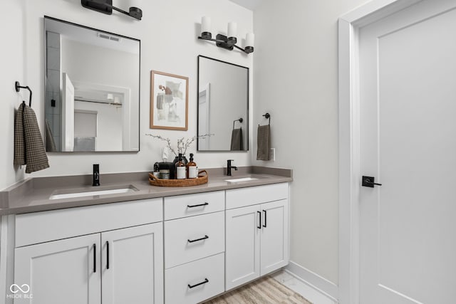 bathroom with visible vents, a sink, baseboards, and double vanity