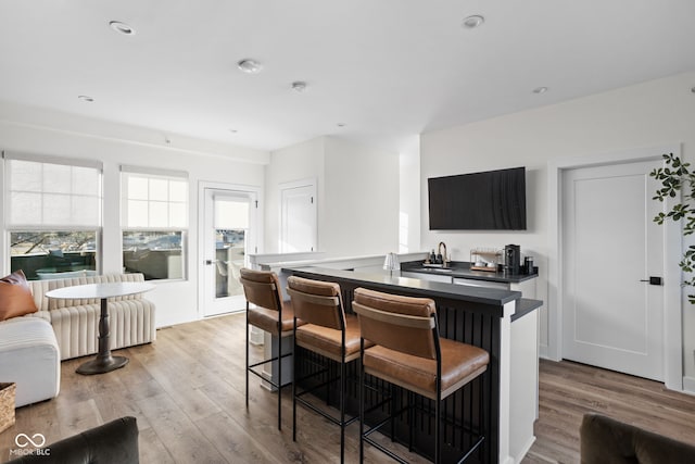 kitchen featuring dark countertops, a kitchen breakfast bar, and wood finished floors