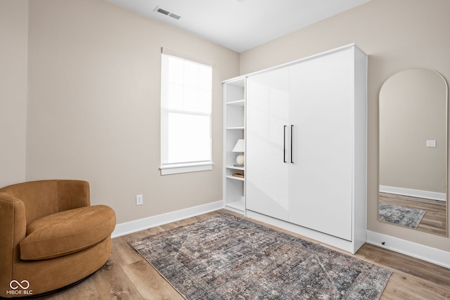 living area featuring wood finished floors, visible vents, and baseboards