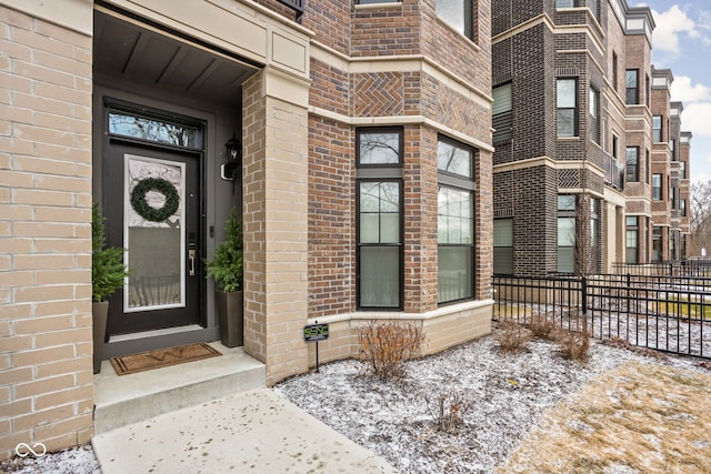 entrance to property featuring fence and brick siding