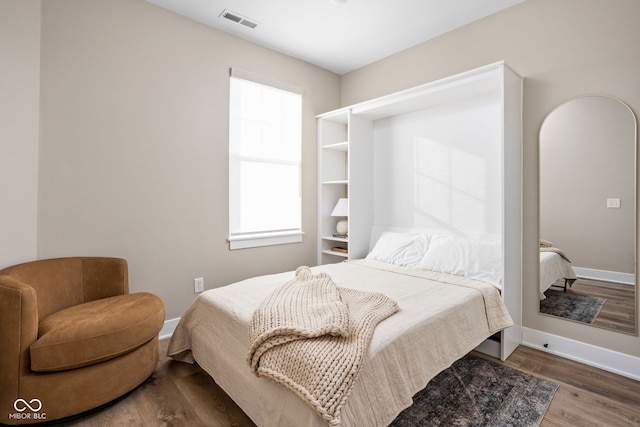 bedroom featuring baseboards, visible vents, and wood finished floors