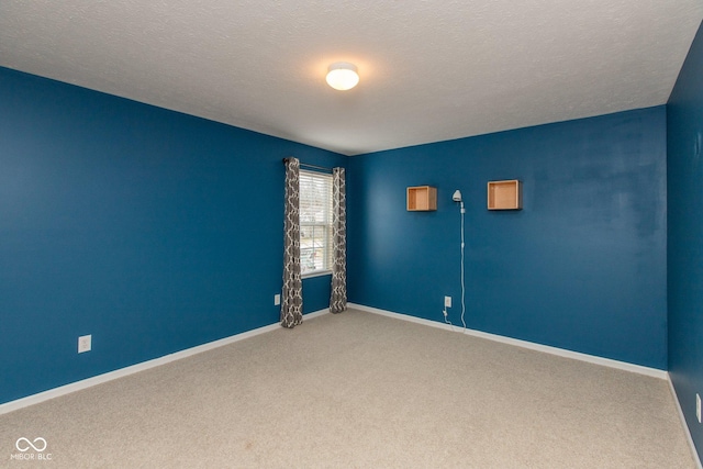 carpeted spare room with a textured ceiling and baseboards