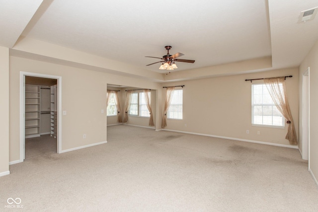 unfurnished bedroom featuring a raised ceiling, visible vents, and light colored carpet