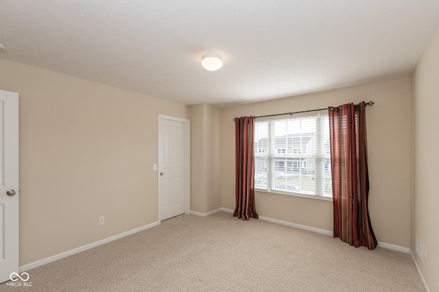 empty room featuring light colored carpet and baseboards