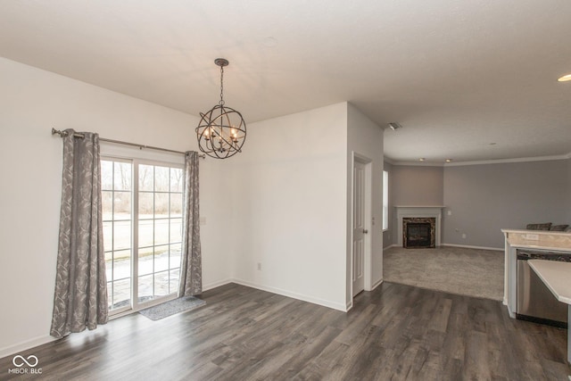 unfurnished dining area with dark wood finished floors, a notable chandelier, a fireplace, and baseboards