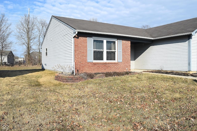 view of side of property featuring a yard, a shingled roof, and brick siding