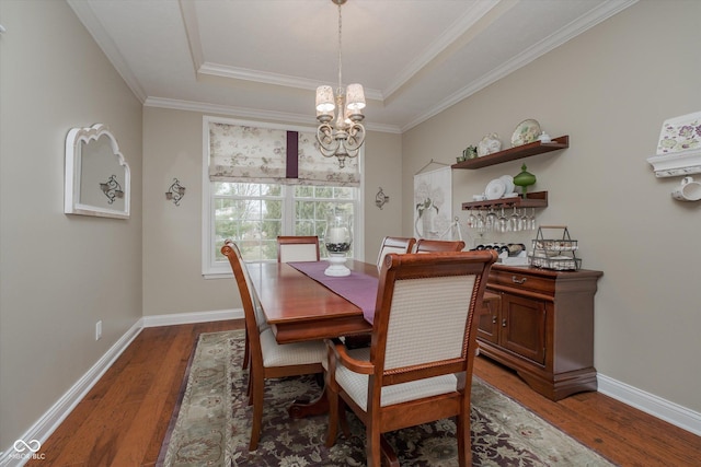 dining space with a chandelier, wood-type flooring, a raised ceiling, and baseboards