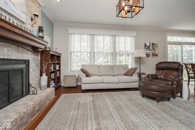 living area featuring a chandelier, a brick fireplace, wood finished floors, and crown molding