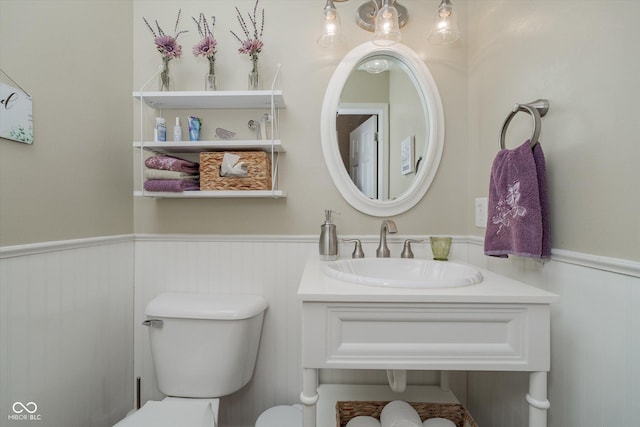 bathroom featuring a wainscoted wall, a sink, and toilet