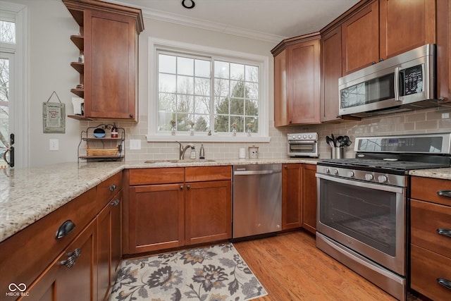 kitchen featuring light wood-style flooring, a sink, ornamental molding, appliances with stainless steel finishes, and open shelves