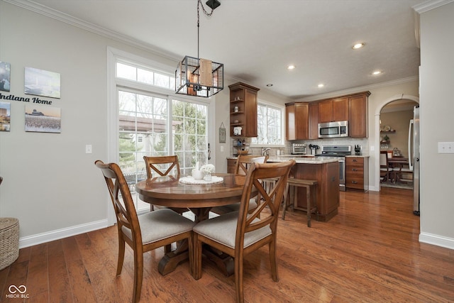 dining space featuring baseboards, arched walkways, dark wood-style flooring, crown molding, and recessed lighting