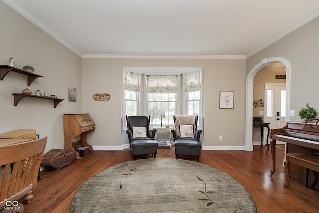 sitting room with ornamental molding, hardwood / wood-style floors, arched walkways, and baseboards