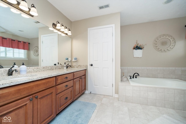 bathroom with double vanity, a garden tub, visible vents, and a sink