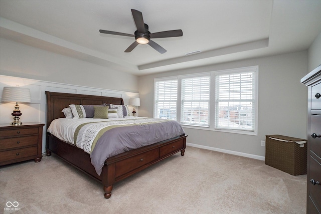 bedroom with light carpet, visible vents, baseboards, and a tray ceiling