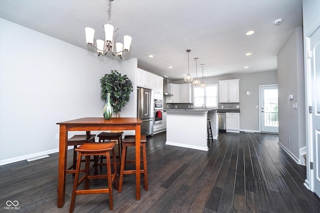 dining area with dark wood finished floors, a notable chandelier, recessed lighting, and baseboards