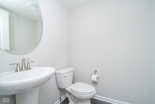 bathroom featuring toilet, visible vents, baseboards, and a sink