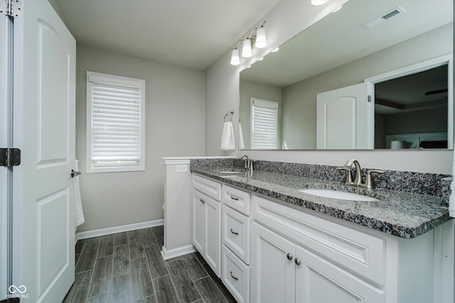 bathroom with visible vents, baseboards, wood finish floors, and a sink