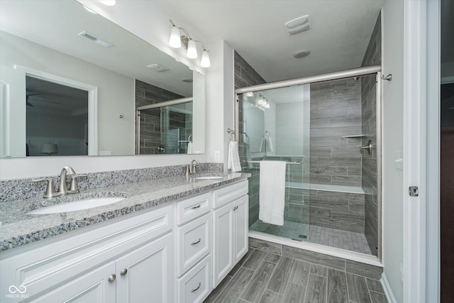 bathroom featuring a sink, visible vents, double vanity, and a shower stall