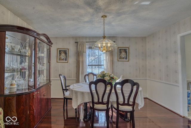 dining area featuring wallpapered walls, a textured ceiling, and dark wood-style flooring