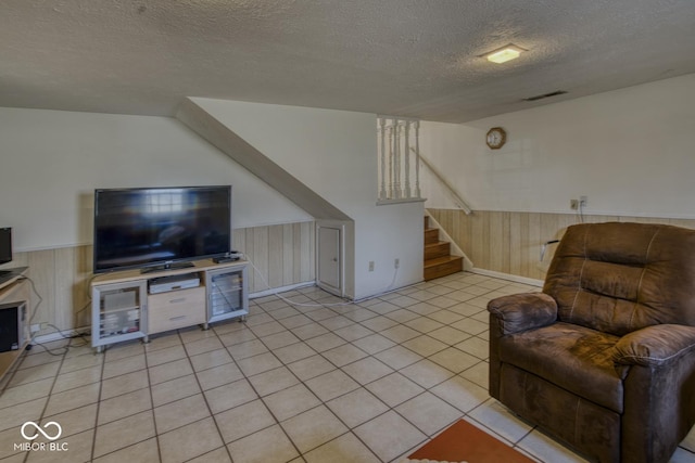 living area with wooden walls, stairs, visible vents, and wainscoting